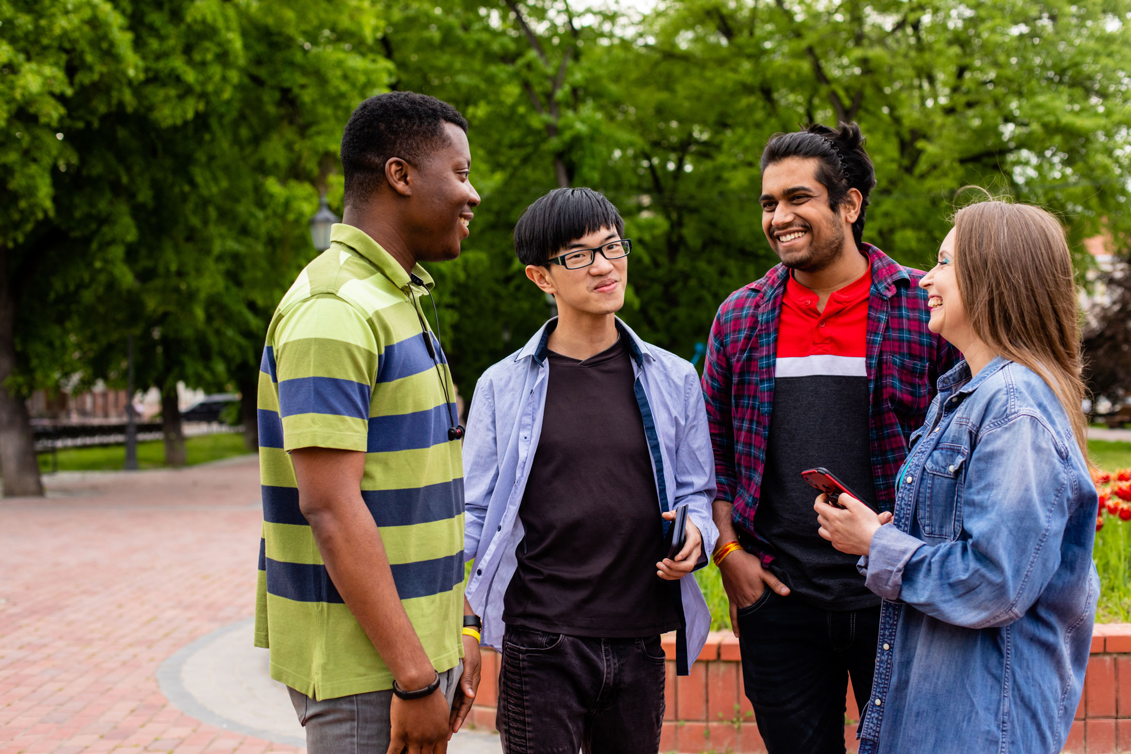 Four students of different ethnicities talking and having fun in a university campus.